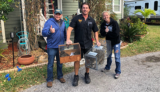 Odessa FL Couple Posing with Pest Control Expert Holding Two Cages Containing Squirrels